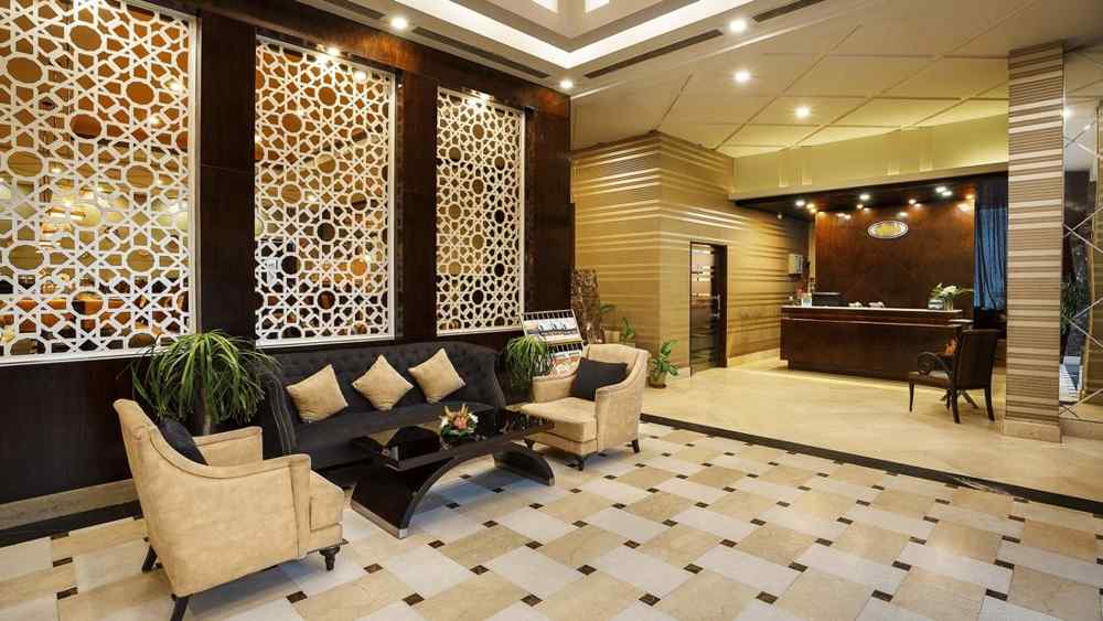 A sophisticated hotel lobby featuring a geometric patterned boards, plush seating, and a reception desk - The Manor, Bareilly