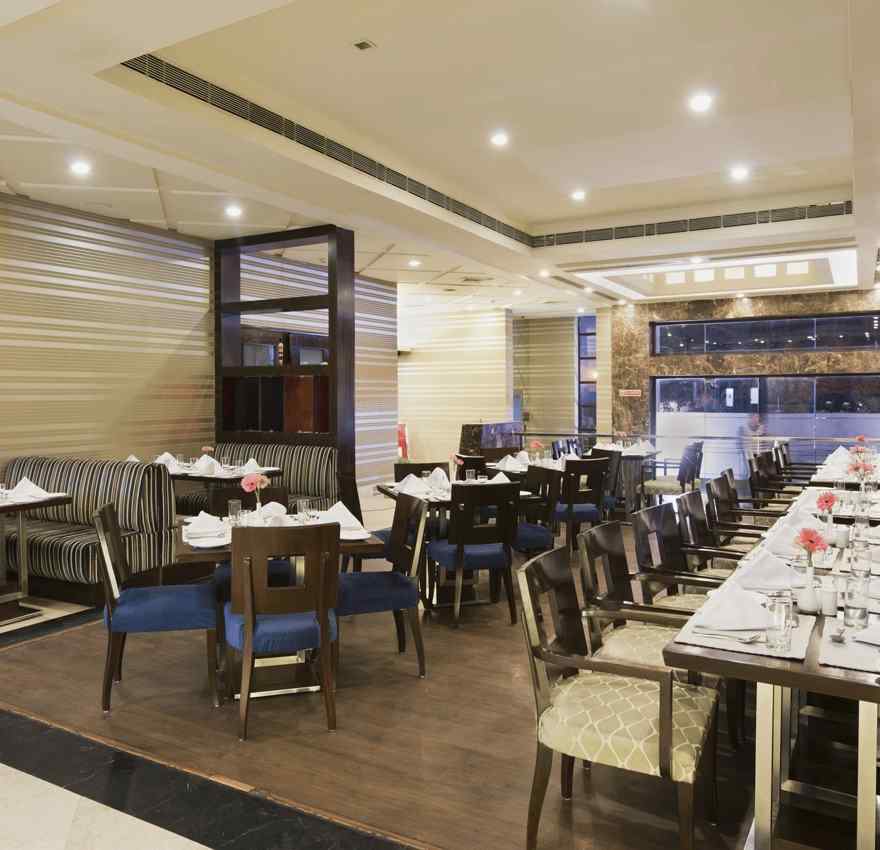 A closed dining space at The Manor Bareilly featuring multiple wooden tables and chairs arranged for a dining experience