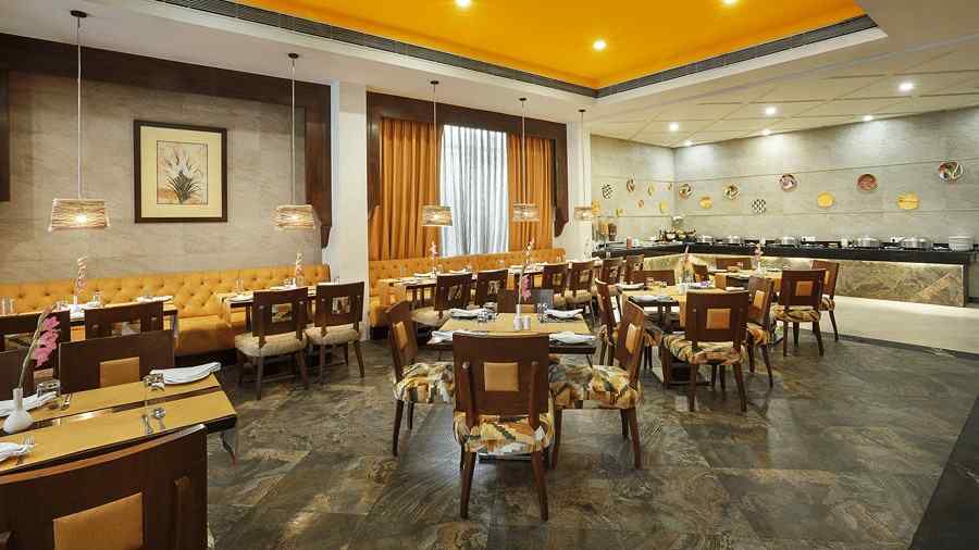A bright and inviting dining space with yellow ceiling, stylish lighting and chair seating for guests - The Manor, Bareilly