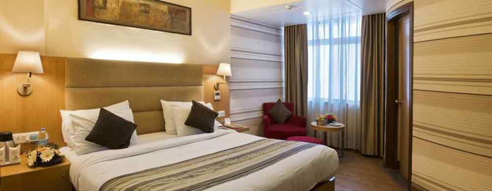 A bedroom with a headboard and an elegant portrait hanging on the wall behind it at The Manor, Bareilly 