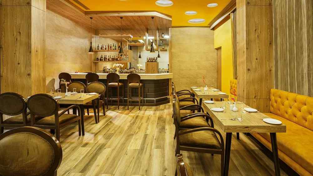 A bar setting at The Manor in Bareilly, featuring wooden tables and shelves lined with various bottles