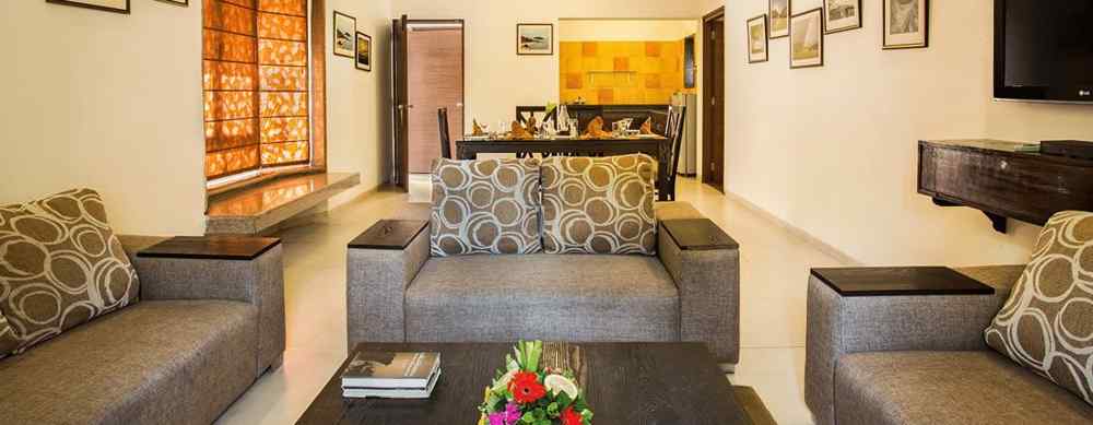 An image of a seating area with photos hanged on the wall, flat TV screen,  and behind the seating area there is a dining table set - The Riverview Retreat, Corbett