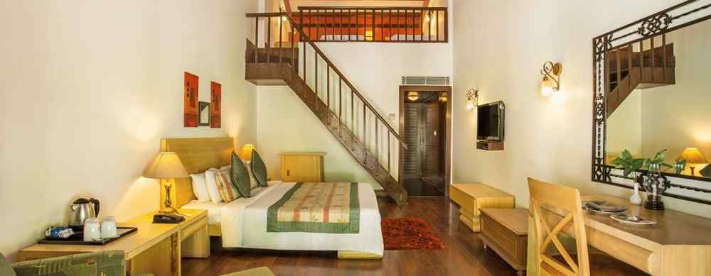 An image of a room with internal stairs leading to the attic, a king size bed, seating area  with chair, tables, and sofa - The Riverview Retreat, Corbett