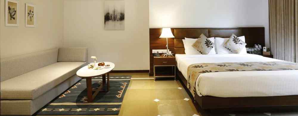 An image of a master suite bedroom with king size bed, a bedside table next to it with a lamp, and a sofa with centre table - The Riverview Retreat, Corbett