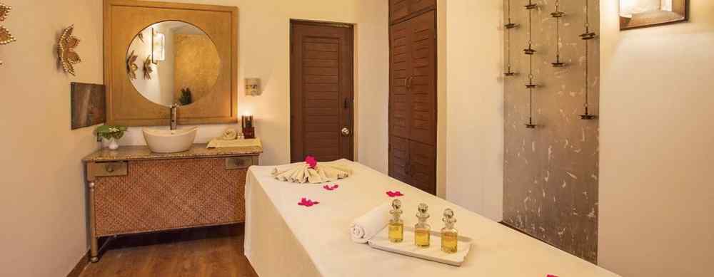 Spa therapy room at The Riverview Retreat, Corbett featuring a neatly arranged massage bed with aromatic oils, elegant wash basin, decorative lighting, wooden accents and a serene ambience for relaxing wellness treatments.