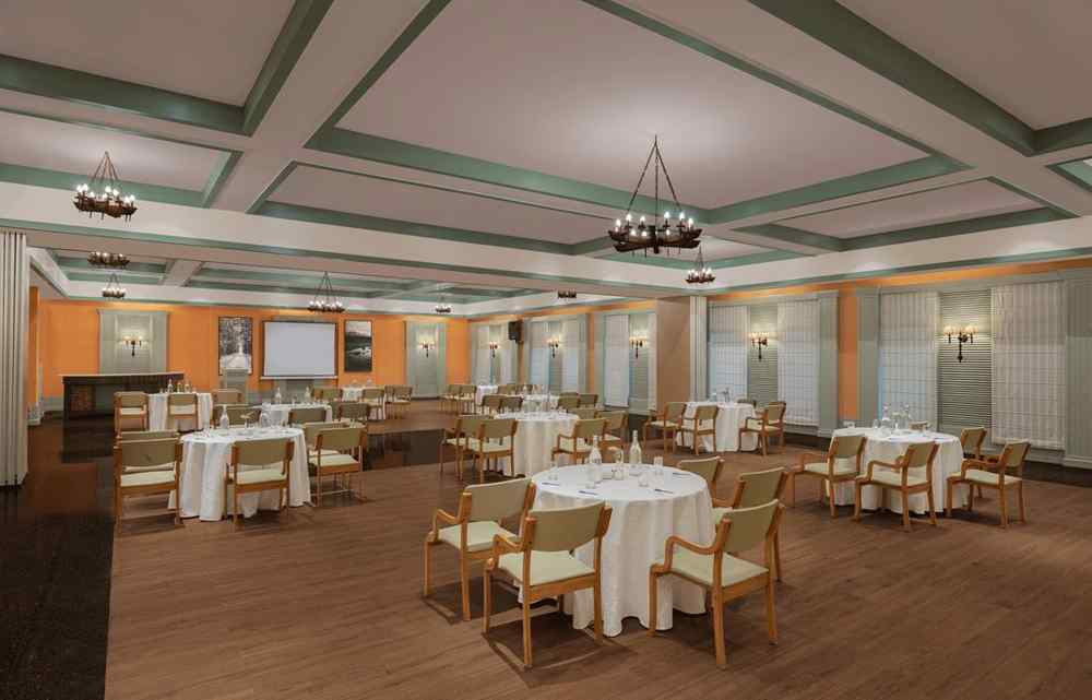 An image of a conference hall with a set of table and chairs in each corner and a projector screen at the front of the room - The Riverview Retreat, Corbett