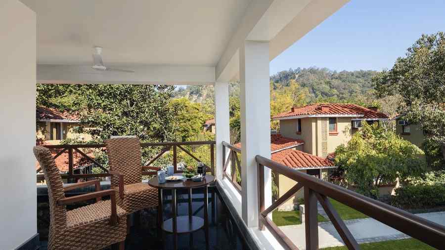 An image of a balcony with two wooden chairs - An image of an outdoor dining area beside a lake - The Riverview Retreat,  Corbett