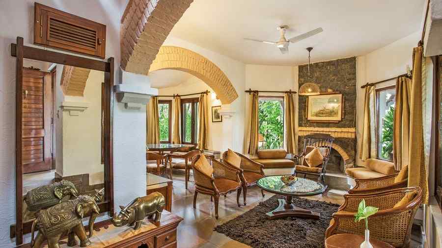 An image of a living area with many valuable and decorative items kept at top of the cabinet and near that there is a wooden sofa set - The Riverview Retreat, Corbett