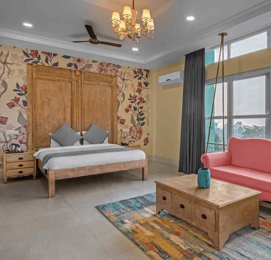 An image featuring a spacious bedroom with a king-size bed, a sofa, and a large window with a view - atman, dharamshala
