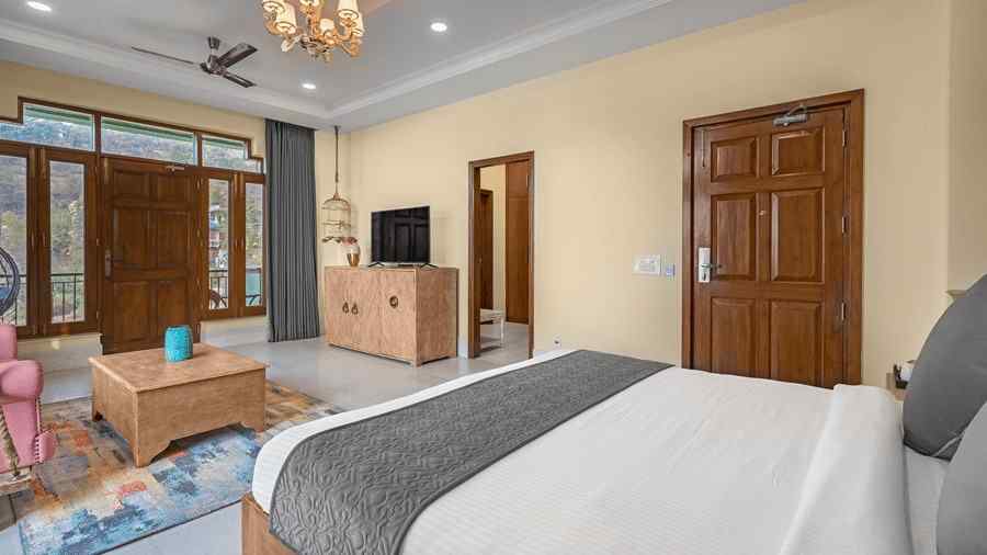 a bedroom with a lamp on the ceiling in the centre of the room, with a large bed placed against the wall and a television placed on a drawer - Atman, Dharamshala