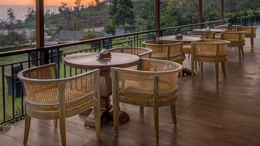 The Fuzion cafe located on a deck with views of the forest and clusters of tables and chairs in a line - Atman, Dharamshala