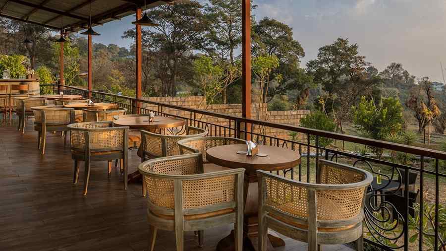 a cafe located on a deck with views of the forest and clusters of tables and chairs in a line - Atman, Dharamshala
