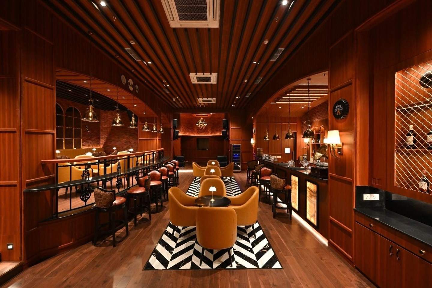 Bass & Barrel restaurant interior with dark timber panelling, brass pendant lights and warm lamplight at Peerless Hotels, Kolkata