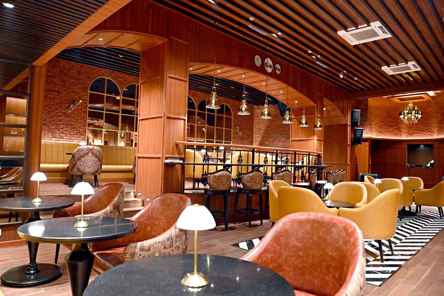 Bass & Barrel restaurant seating with timber arches, exposed brick and warm table lamps at Peerless Hotels, Kolkata