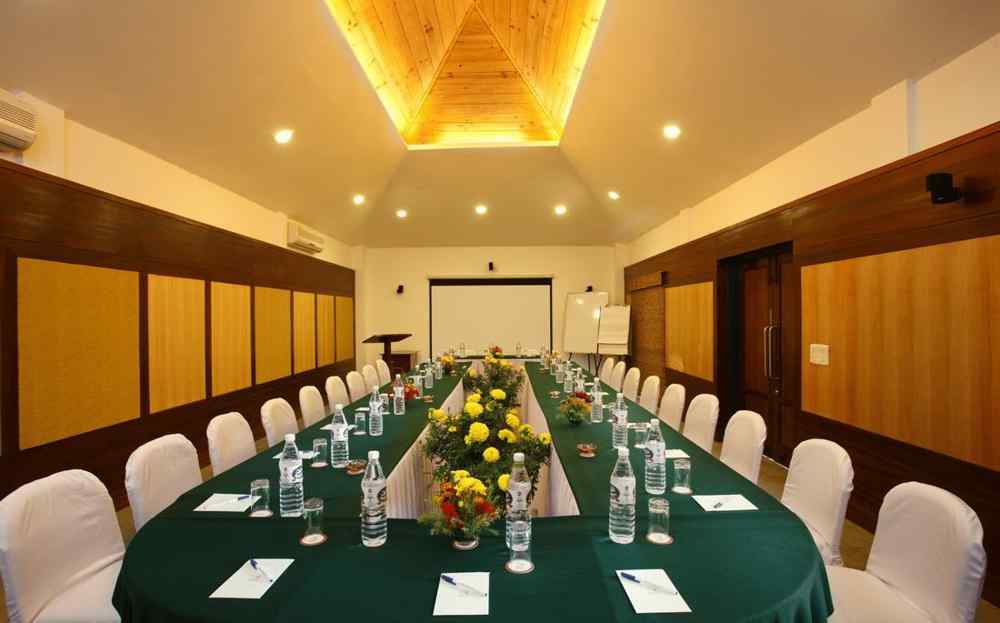 Conference hall with arranged chairs and projector at baikunth Resort, Kasauli 