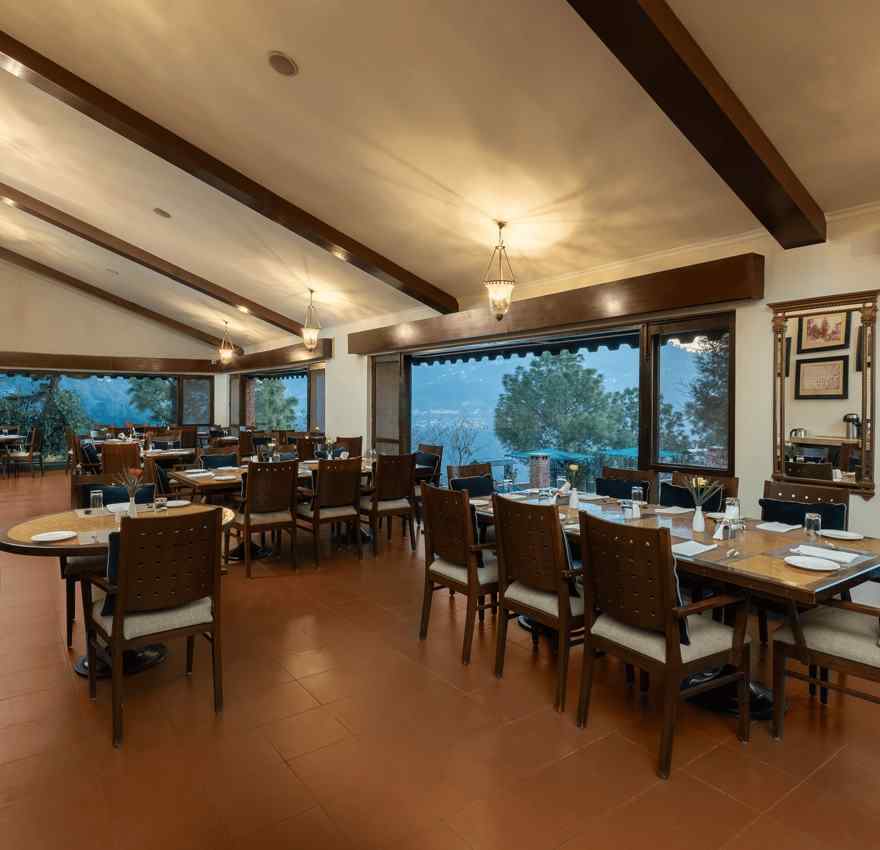 Restaurant area during evening time with lights on  fully wooden furnished with a beautiful view at Baikuth resort, kasauli.