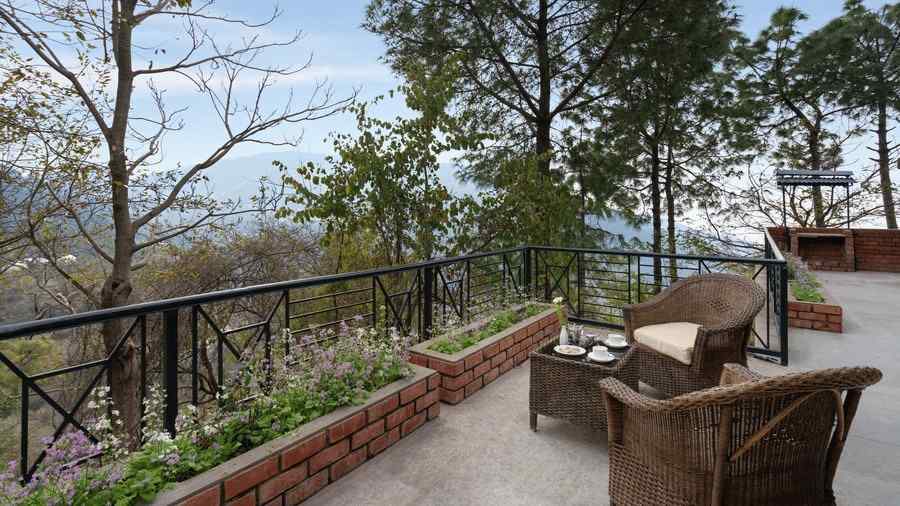 Superior Cottage Hill views sitting area with wooden chairs and beautiful view at Baikuth resort, kasauli.