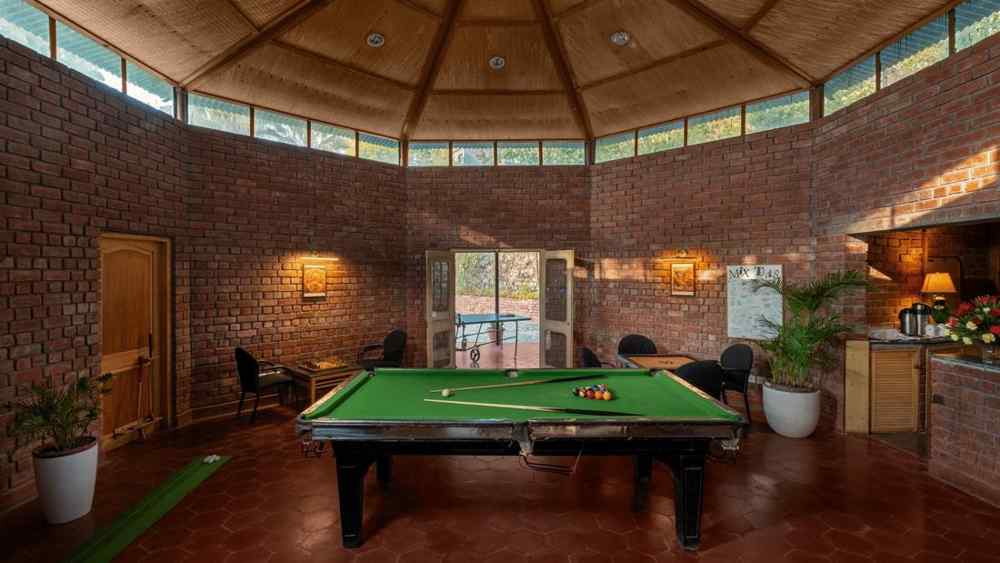 A pool area with a glass roof, indoor plants and room is illuminated by lights -  Baikunth resort, kasauli 