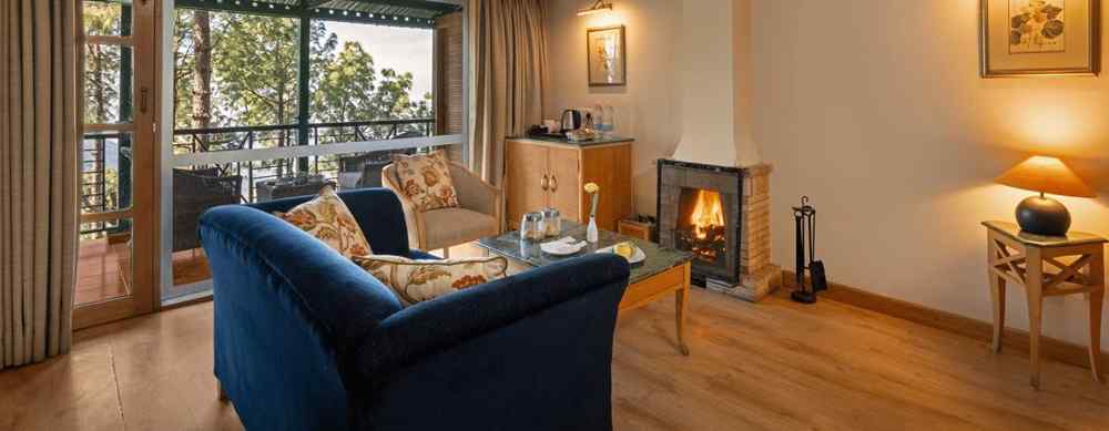 Premium Cottage sitting area with a comfy sofa, a view through window and fireplace in front of sofa at Baikunth resort, kasauli.