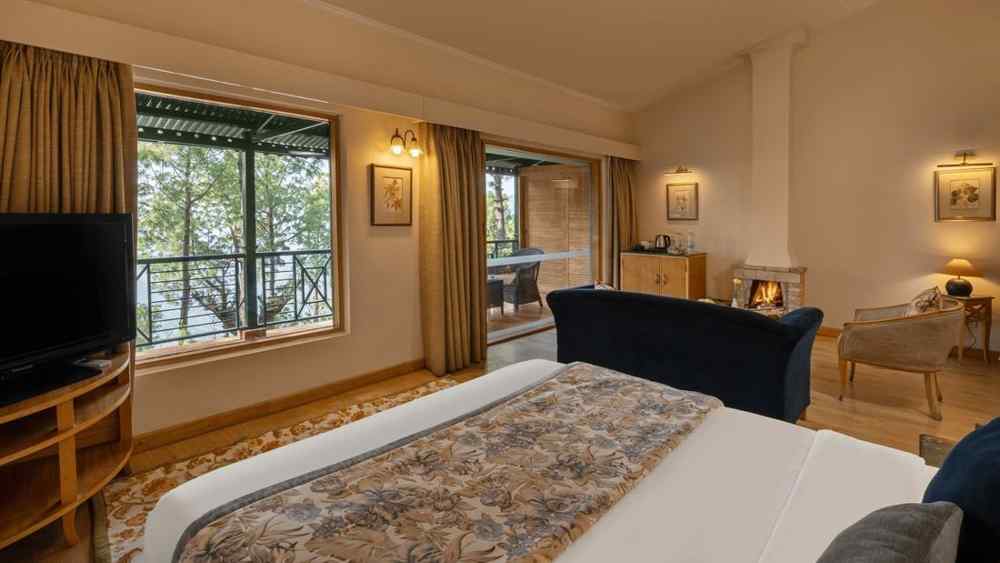 A premium cottage room featuring a cosy bed, open windows, and wall light fixtures that create a warm ambience -  Baikunth resort, kasauli 