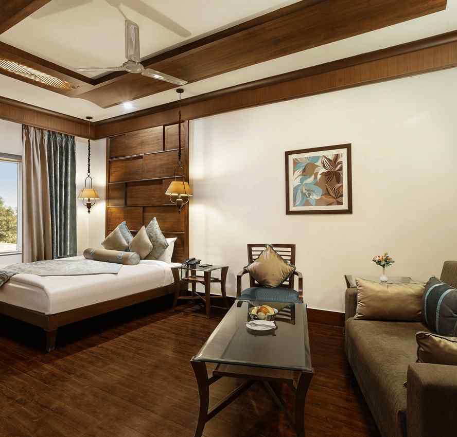 a view of a bedroom with a large bed in the corner and a sofa with a table - The Manor, Kashipur