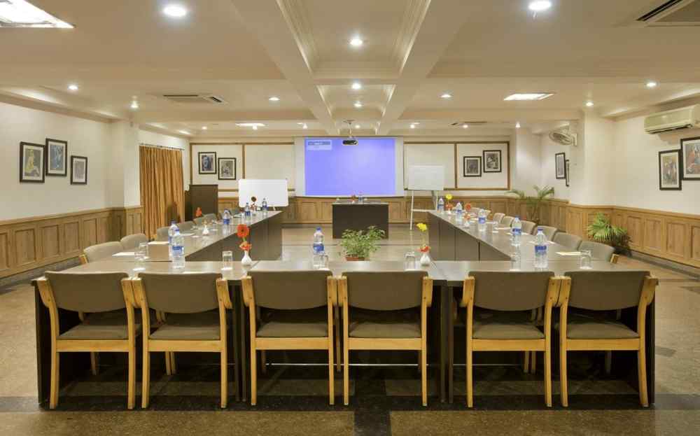 a front view of a conference room with a U-shaped seating arrangement and the projector on the other end of the room