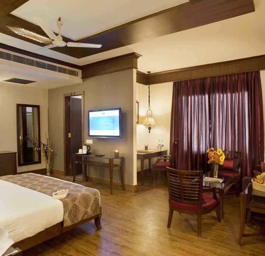 A view of a bedroom with a single bed facing a television and a desk with chairs - The Manor, Kashipur