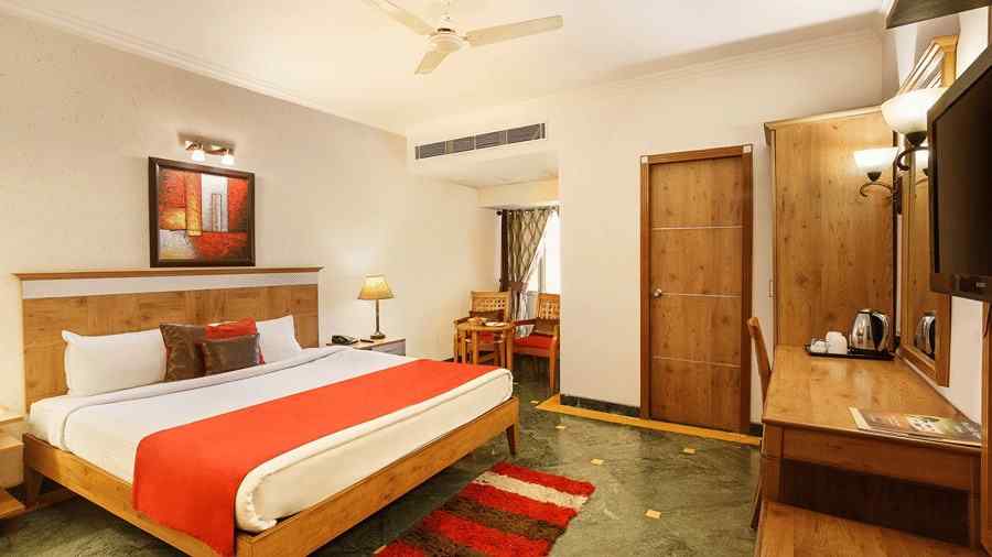 a view of a bedroom with a large bed facing a workdesk with a television above the workdesk - The Manor, Kashipur