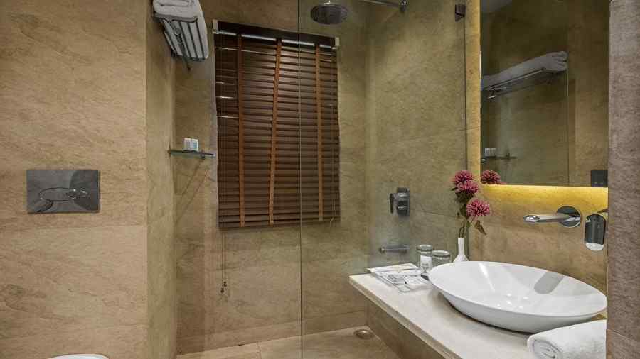 a washroom with a washbasin and toiletries on the right side and a western style toilet on the left - The Manor, Kashipur