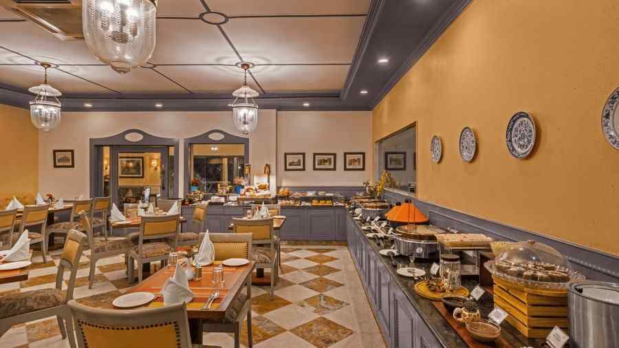an image of a restaurant with a buffet setting and clusters of tables with chairs - The Manor, Kashipur