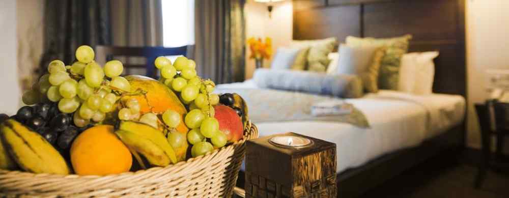 Fruit basket in a room with a bed and huge glass window | The Manor, Kashipur