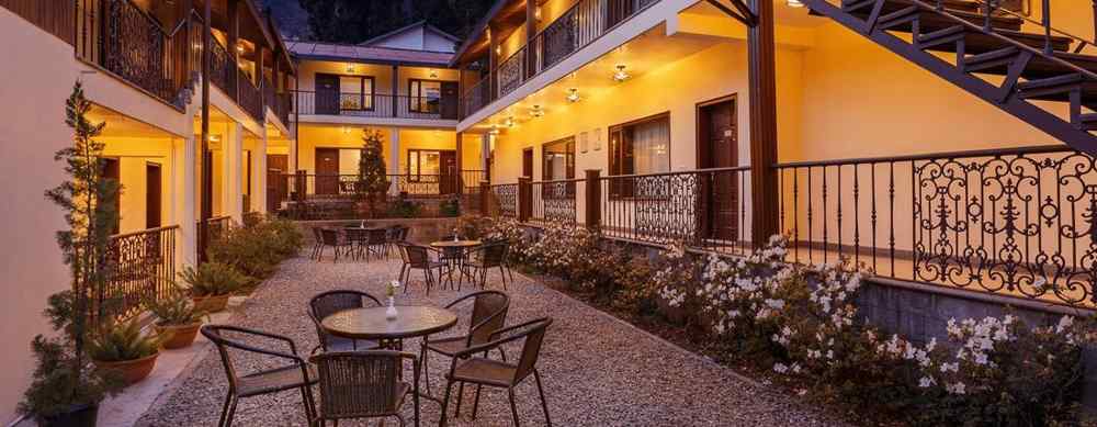 Common area ar The Earl's Court in Nainital in the evening feauturing tables and chairs arranged and a staircase in the corner 