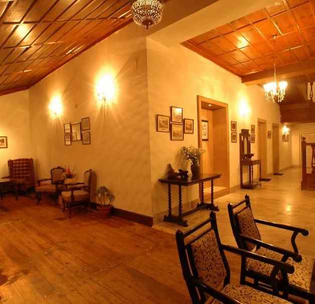 An image of a rooms with timber floors, adjacent to each other, these rooms have wooden chairs and tables with a few flower pots around