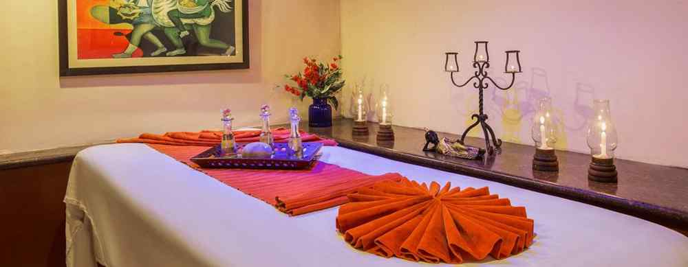 A spa table, candles beside it and a frame on the wall in a treatment room at our Spa in Nainital