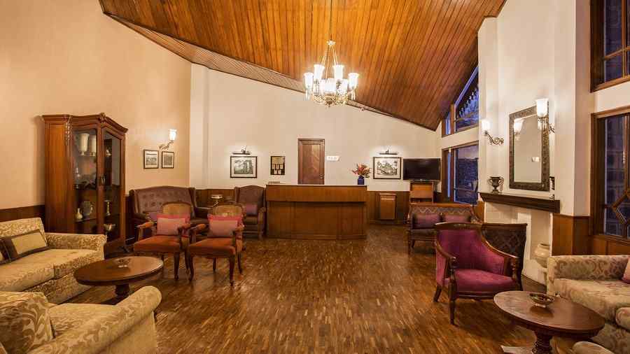 A image featuring interior view of lobby area at the naini retreat, nainital. with wooden flooring and roofing, with a chandelier lit.
