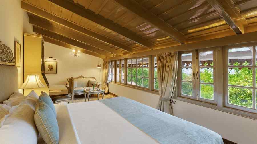 Side view of a room with a bed, sloped roof and glass windows - the naini retreat, nainital.