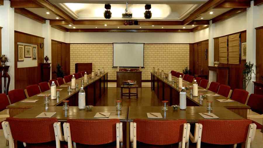 An image of Conference room with  U Shaped Set-up, a projection screen placed at the centre . The room has high ceilings, wooden paneling. The overall ambiance is professional and formal - the naini retreat, nainital.
