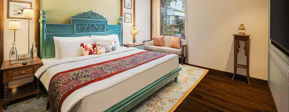 A suite room with a king size bed, elegant wall decors a five leafed fan, a flat screen TV, and multiple wall hangings - The Naini Retreat, Nainital