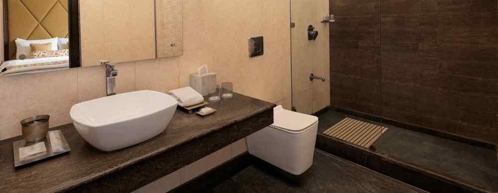 An image featuring a washroom, a big mirror,  the glass separator for bath area - The Naini Retreat, Nainital.