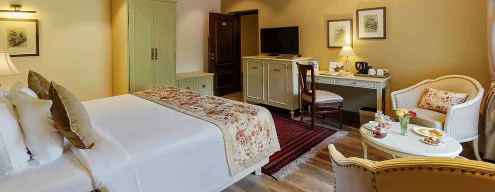 An image, featuring a side view of cosy room with comforting decors, bed, wooden ceiling - The Naini Retreat