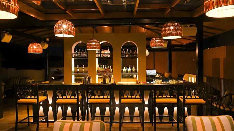 Contemporary bar lounge at The Terrace, Aloha on the Ganges, Rishikesh, with striped seating, wooden interiors, and decorative pendant lights.