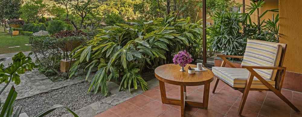 An image featuring outdoor sitting area with a table and chair, set against a backdrop of stunning mountain views.