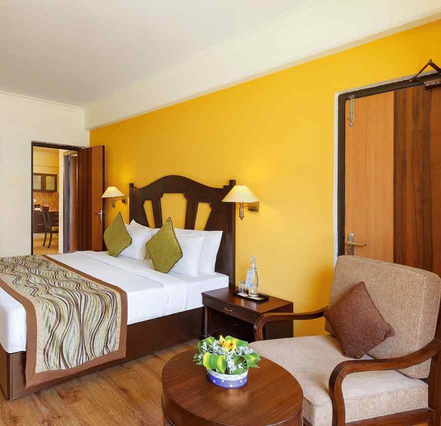 This image showcases a luxurious hotel room of aloha on the ganges, with a warm and inviting atmosphere. The room features a large king-size bed with a plush headboard and comfortable bedding.