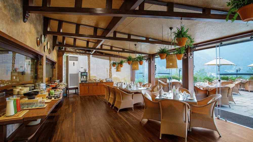 Elegant dining area at Aloha on the Ganges featuring wooden interiors, comfortable seating, large windows, and scenic river-facing views.